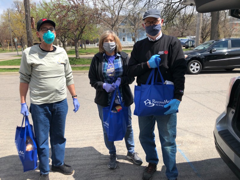 3 volunteers in masks helping with grocery delivery